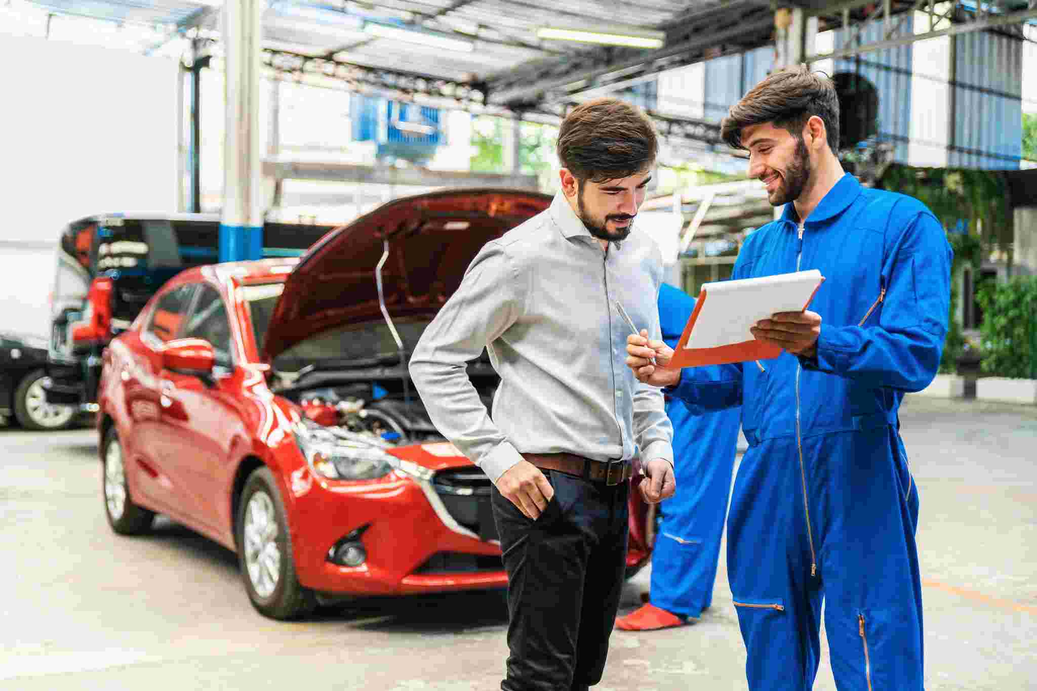 Mechanic showing car checklist to customer.